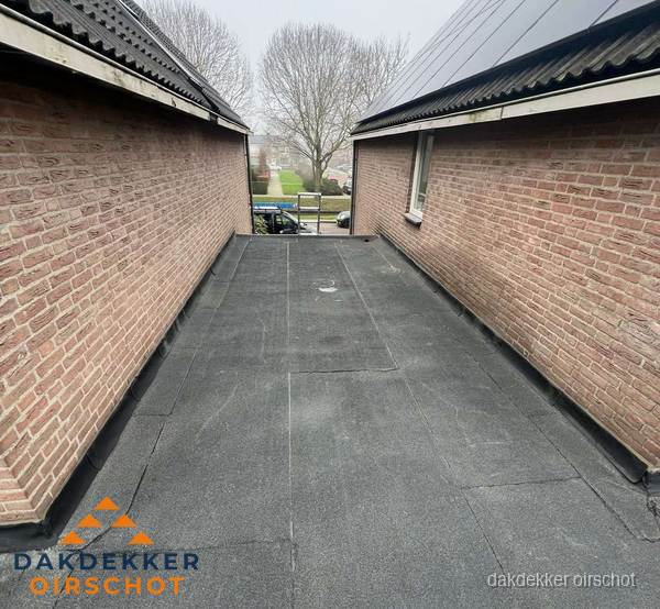 Plat dak met bitumen dakbedekking tussen bakstenen muren in Oirschot Plat dak met bitumen dakbedekking tussen bakstenen muren in Oirschot