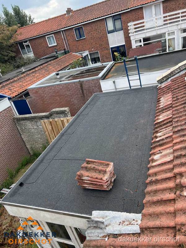 Plat dak aanbouw met bitumen naast schuin pannendak in Oirschot