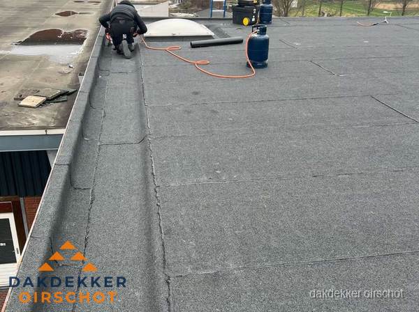 Dakdekker repareert bitumen dakbedekking op groot plat dak in Oirschot