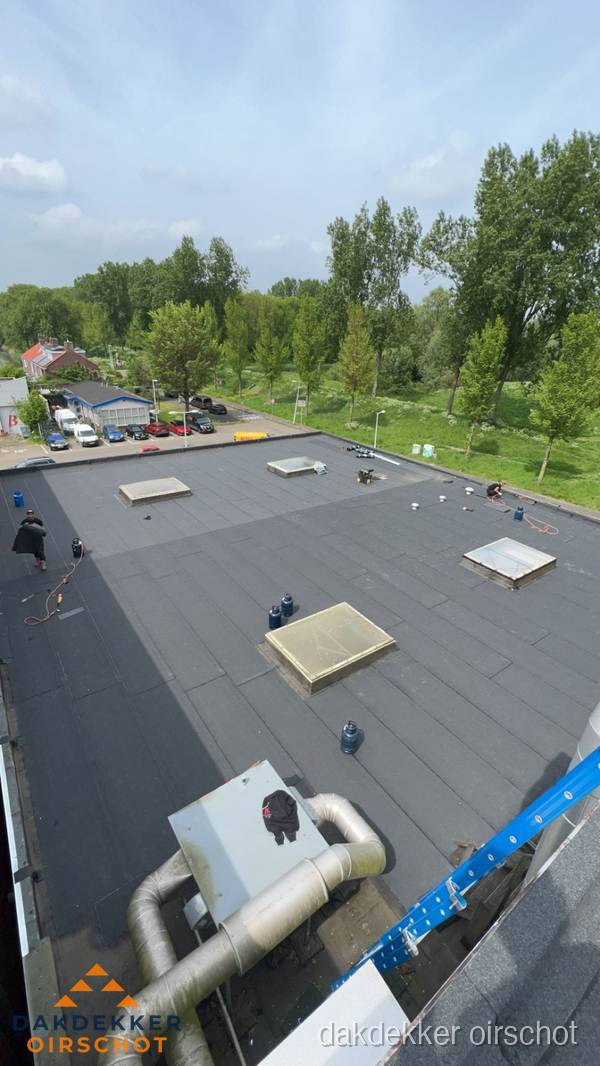 Dakdekker aan het werk op groot plat dak met bitumen in Oirschot