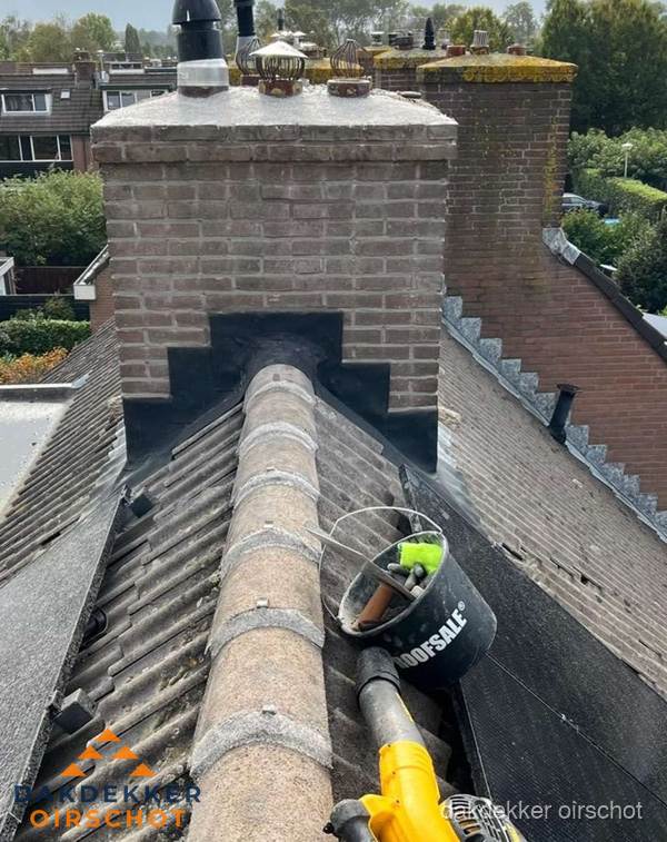 Schoorsteen met loodaansluiting en nokvorst op pannendak in Oirschot