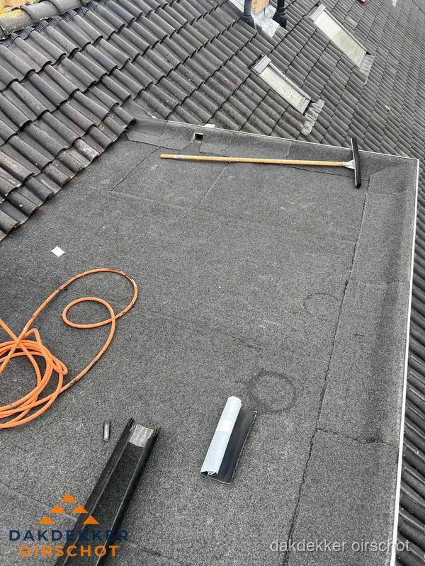 Plat dak reparatie met gereedschap en loodstroken in Oirschot