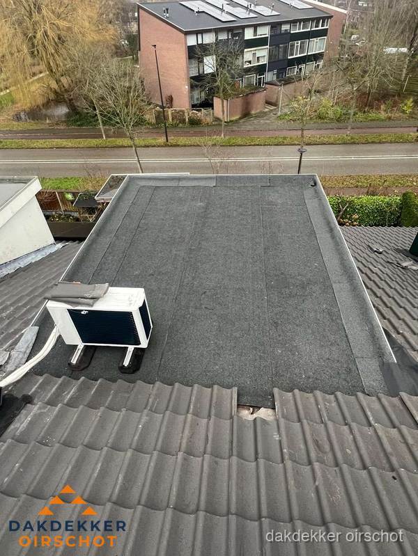 Plat dak inspectie met bitumen bedekking naast schuin pannendak in Oirschot